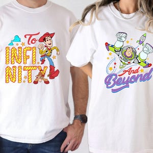 May include: Two white t-shirts with Toy Story designs. One features Woody with the words "To Infinity". The other shows Buzz Lightyear with "And Beyond". Both shirts have vibrant, colourful graphics.