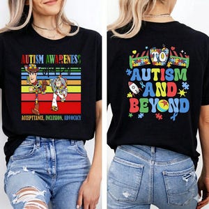 K&ouml;nnte beinhalten: Schwarzes T-Shirt mit einem farbenfrohen Design f&uuml;r Autismus-Aufkl&auml;rung. Auf der Vorderseite sind Woody und Buzz Lightyear mit dem Text "Autism Awareness, Acceptance, Inclusion, Advocacy" abgebildet. Auf der R&uuml;ckseite steht "To Autism and Beyond" mit Puzzleteilen und einer Rakete.