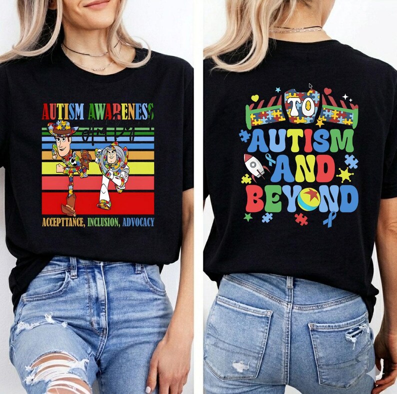 K&ouml;nnte beinhalten: Schwarzes T-Shirt mit einem farbenfrohen Design f&uuml;r Autismus-Aufkl&auml;rung. Auf der Vorderseite sind Woody und Buzz Lightyear mit dem Text "Autism Awareness, Acceptance, Inclusion, Advocacy" abgebildet. Auf der R&uuml;ckseite steht "To Autism and Beyond" mit Puzzleteilen und einer Rakete.