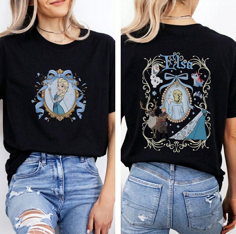 May include: Black t-shirt featuring a front and back design. The front displays a framed image of a blonde woman in a blue dress, with blue ribbons. The back features the name "Elsa" and a similar framed image with other characters.