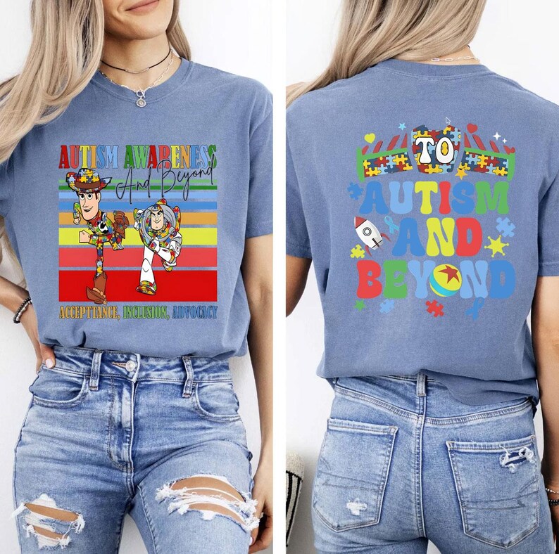 K&ouml;nnte beinhalten: Hellblaues T-Shirt mit der Aufschrift "AUTISM AWARENESS And Beyond" und den Zeichentrickfiguren Woody und Buzz Lightyear. Auf der R&uuml;ckseite des Shirts steht "TO AUTISM AND BEYOND" mit einer Rakete und Puzzleteilen.