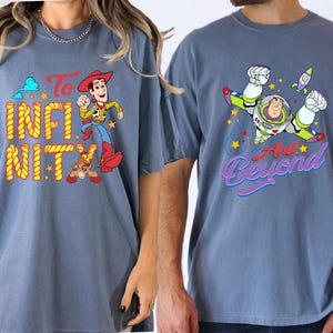 May include: Two blue t-shirts featuring characters from Toy Story. One shirt displays Woody with the words "To Infinity", the other Buzz Lightyear with "And Beyond". Both shirts have colourful graphics.