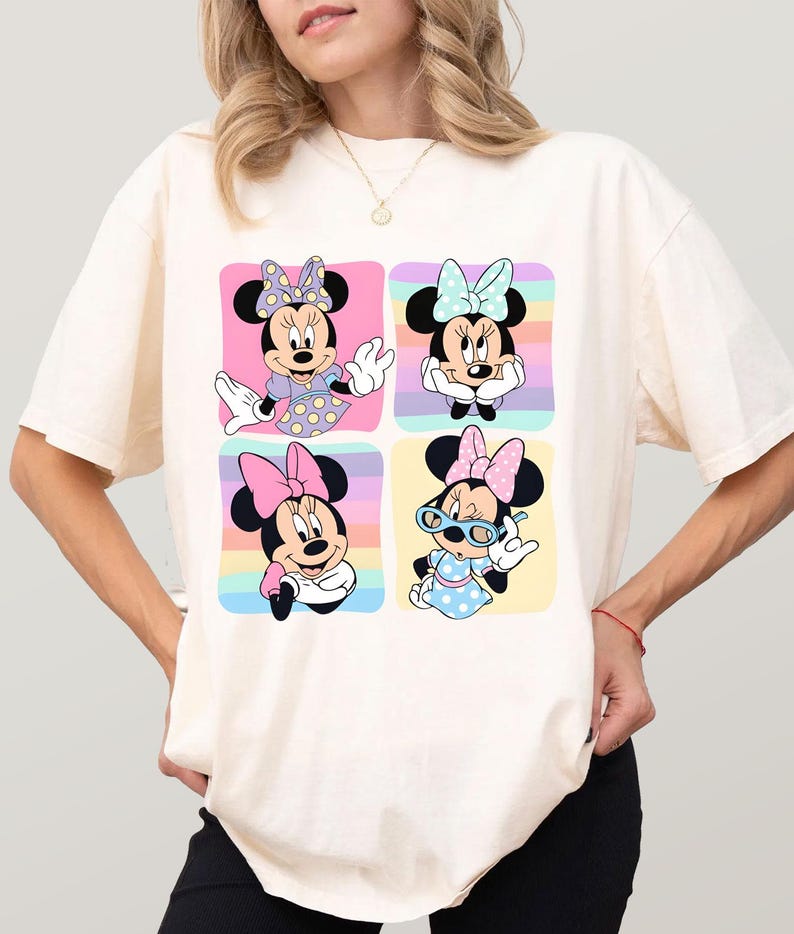 Może przedstawiać: Kremowy t-shirt z kolorową grafiką Myszki Minnie w czterech r&oacute;żnych pozach. Każda poza jest umieszczona w kwadracie z pastelowym tęczowym tłem. Myszka Minnie ma na sobie r&oacute;żne stroje i kokardy.