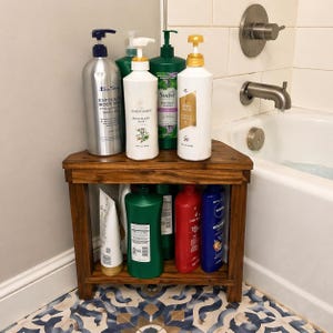 May include: A wooden corner shelf holds various bath products, including body wash, shampoo, and conditioner. The shelf is made of dark wood and is placed near a bathtub with a silver faucet. The products are in various colored bottles and tubes.