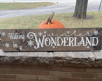 May include: A wooden sign with white lettering that reads "Walking in a Winter Wonderland". The sign is brown and has a rustic look.