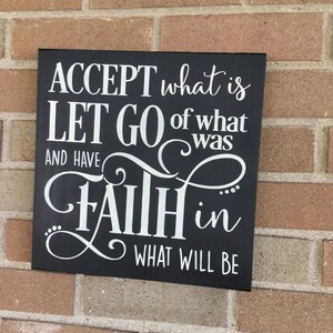 May include: Black wooden sign with white lettering that reads "ACCEPT what is LET GO of what was AND HAVE FAITH in WHAT WILL BE".
