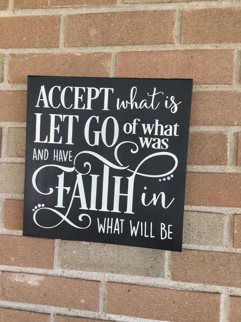 May include: Black wooden sign with white lettering that reads "ACCEPT what is LET GO of what was AND HAVE FAITH in WHAT WILL BE".