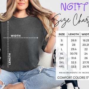 May include: A size chart for Comfort Colors 1717 t-shirts, with measurements in inches. The chart includes sizes S to 4XL, with corresponding length and width measurements. The image also shows a person wearing a dark grey t-shirt.