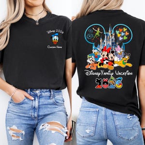 Op de afbeelding: Zwart T-shirt met Disney-personages en tekst. De voorkant toont Donald Duck en "Disney 2026" met ruimte voor een aangepaste naam. De achterkant toont Mickey, Minnie en andere personages met "Disney Family Vacation 2026".