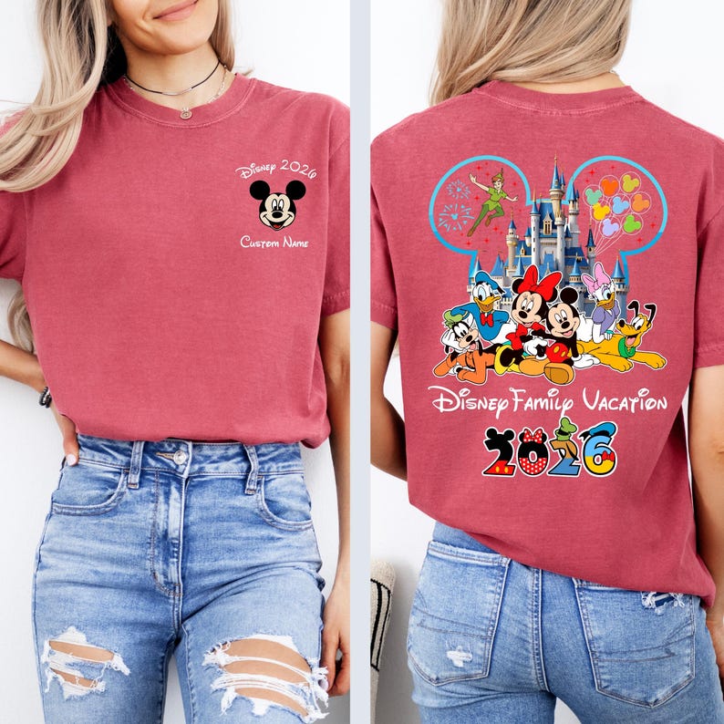 Op de afbeelding: Rood t-shirt met Mickey Mouse en de tekst "Disney 2026" op de voorkant. De achterkant van het shirt toont Disney-personages, een kasteel en de woorden "Disney Family Vacation 2026".