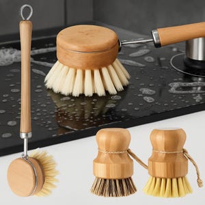 Puede incluir: Colección de cepillos de cocina de madera con cerdas naturales. Los cepillos tienen mangos de madera de color claro y cabezales de cepillo circulares. Uno tiene un mango largo, mientras que otros son compactos. Las cerdas son claras u oscuras.