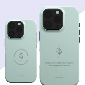Peut inclure: Deux coques de téléphone vert clair. Chaque coque a une découpe pour l'appareil photo et un petit motif floral. Le texte sur les coques se lit "Bold power and glorious majesty are wrapped around her."