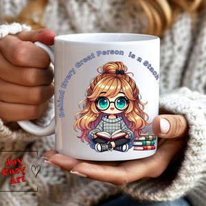 Puede incluir: Taza de cerámica blanca con una ilustración de dibujos animados de una niña con cabello rubio y gafas leyendo un libro. El texto en la taza dice "Behind Every Great Person is a Stack".