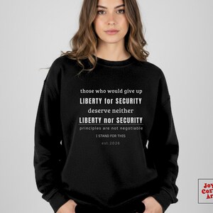 Puede incluir: Sudadera negra con texto blanco: "aquellos que renunciarían a la LIBERTAD por la SEGURIDAD no merecen ni LIBERTAD ni SEGURIDAD los principios no son negociables I STAND FOR THIS est. 2026".