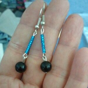 May include: A pair of dangle earrings with black beads and blue glass beads.