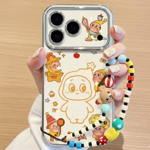 Puede incluir: Una funda de teléfono blanca con un diseño de personaje de dibujos animados y una correa de muñeca con cuentas. La funda presenta múltiples personajes de dibujos animados amarillos y naranjas, con un borde transparente. La correa de muñeca tiene cuentas de colores y un pequeño dije de oso.