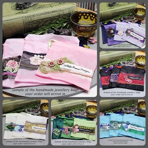 May include: A collection of small fabric drawstring pouches in various colors including pink, purple, black, white, green, and blue. Each pouch features decorative lace trim, floral appliques, and a white label reading White Raven Designs.