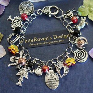 May include: A silver-tone charm bracelet featuring various pendants including a tree, a spider, a snake, wings, a mermaid, and an oval tag with the text "Well behaved women rarely make history." The bracelet includes red, black, and textured copper beads.