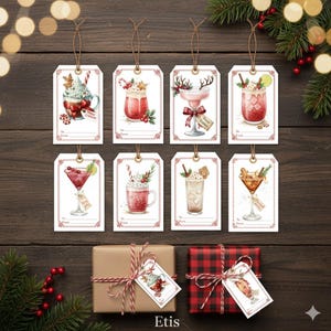 May include: A collection of Christmas-themed gift tags featuring watercolor illustrations of festive cocktails. Each tag has a unique design with holiday decorations and the words "To: From:" for personalization. The tags are tied with twine and displayed on a wooden surface.