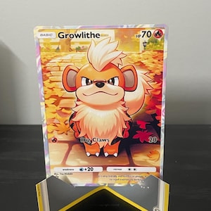 May include: A Growlithe Pokémon trading card with a colorful illustration of the character. The card features the name "Growlithe", HP 70, and the "Dig Claws" attack. The background shows an autumn scene with fallen leaves.