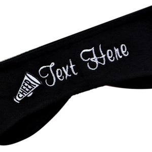 May include: Black headband with white embroidery of a cheerleader megaphone and the text "Text Here".