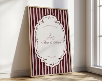 May include: A framed wedding welcome sign with a burgundy and white striped background. The sign features an ornate white frame with the text "Welcome to our wedding", a swan illustration, and the names "Anna & Simon" with the date "October 19, 2020".