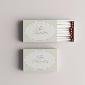 Puede incluir: Dos cajas de cerillas verde claro con el texto "The Morettis" en un dise&ntilde;o ovalado. Una caja est&aacute; abierta, revelando cerillas blancas con puntas marrones. Tambi&eacute;n se ve el texto "October 19, 2013" y "Willowbrook, NY".