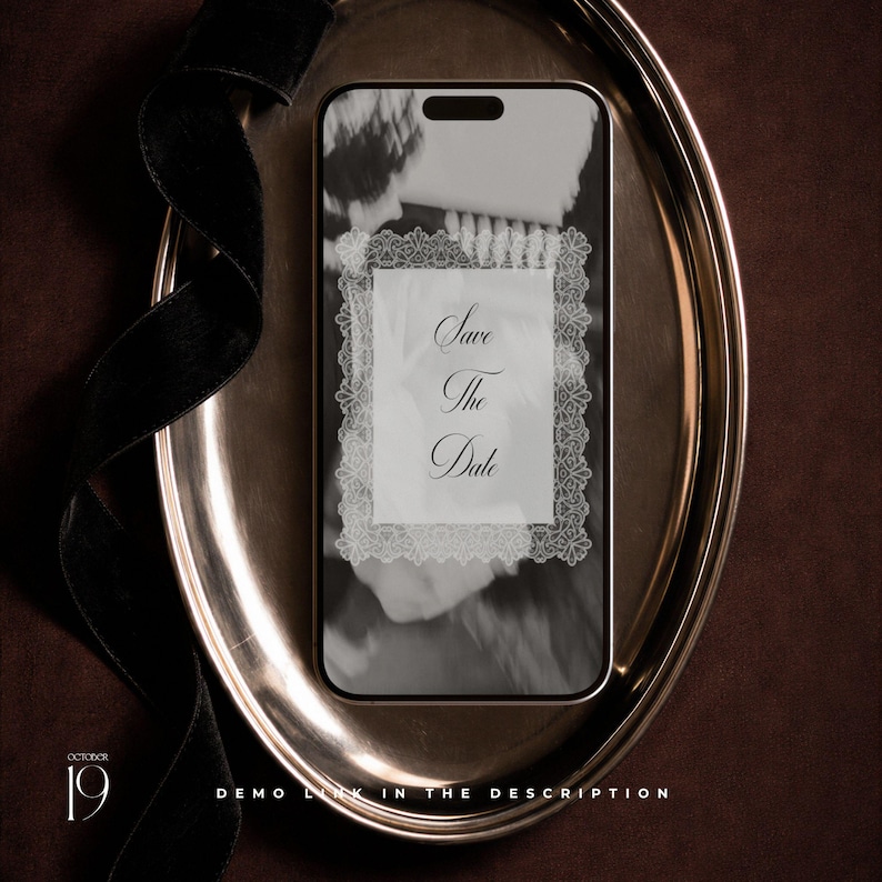 May include: A smartphone displaying a Save The Date announcement with a white lace-style border on a black and white background. The phone rests on an oval silver tray accompanied by a black velvet ribbon. Text includes October 19 and Demo Link.