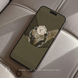 K&ouml;nnte beinhalten: Ein Smartphone, das eine digitale Einladung auf seinem Bildschirm anzeigt. Das Design zeigt einen dunkelolivgr&uuml;nen Hintergrund mit einem cremefarbenen Wachssiegel in der Mitte, einem dekorativen wei&szlig;en Filigranrahmen und den kursiven Buchstaben EM.