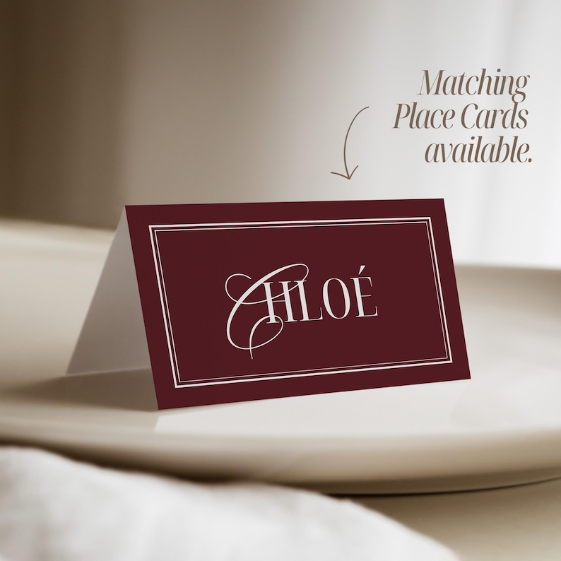Puede incluir: Una tarjeta de mesa burdeos con el nombre "CHLO&Eacute;" en elegante escritura blanca. La tarjeta tiene un borde blanco y se muestra en un plato blanco. El texto encima de la tarjeta dice "Tarjetas de Mesa a juego disponibles."