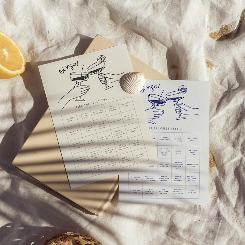 May include: Two bingo cards with cocktail illustrations and the word "Bingo!" in a handwritten font. The cards have fill-in-the-blank prompts like "Has a hidden talent" and "Doesn't like sugar."