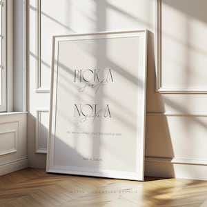 Könnte beinhalten: Ein gerahmtes Hochzeitsschild mit dem Text "PICK A SEAT NOT A SIDE". Das Schild hat einen weißen Rahmen und einen cremefarbenen Hintergrund. Der Text ist in einer stilvollen, eleganten Schriftart gehalten. Der untere Teil des Schildes lautet "WE ARE ALL FAMILY ONCE THE KNOT IS TIED".