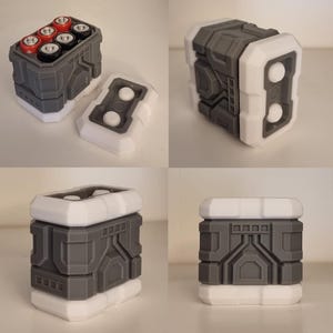 May include: A grey and white 3D-printed battery holder, designed to hold six AA batteries. The holder has a rectangular shape with a removable lid and a futuristic, geometric design. The batteries are visible inside.