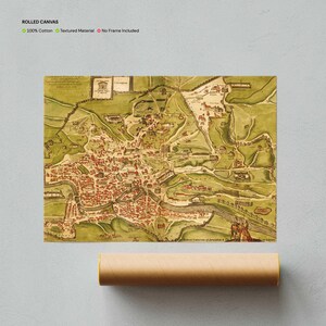 Op de afbeelding: Gerolde canvas print van een vintage kaart, met een gedetailleerde stad met rode gebouwen en groene landschappen. De kaart is gedrukt op een textuurrijk materiaal en wordt opgerold met een bruine papieren koker.