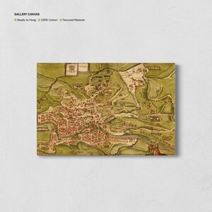 Op de afbeelding: Een canvas print van een vintage kaart, met een gedetailleerde illustratie van een stad met rode gebouwen, groene heuvels en een rivier. Het canvas is klaar om op te hangen en gemaakt van 100% katoen met een textuur.