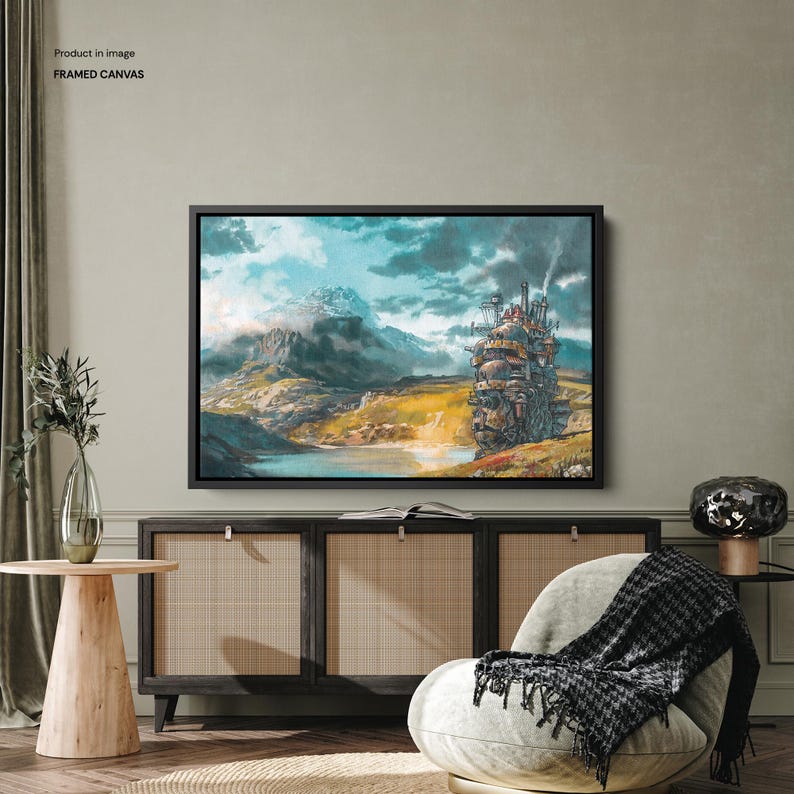 May include: Framed canvas art featuring a fantasy landscape with a large, moving castle and snow-capped mountains. The artwork has a watercolor style with a color palette of blues, greens, and browns. The canvas is framed in black.