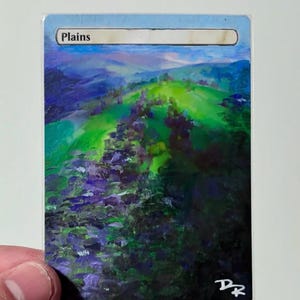 May include: A custom-painted card featuring a landscape scene. The artwork shows a green hill with purple and blue foliage, under a light blue sky. The word "Plains" is printed at the top. The artist's initials are in the bottom right corner.
