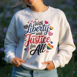 Könnte beinhalten: Weißes Sweatshirt mit dem Text "With Liberty and Justice for All" in einem farbenfrohen Design. Das Design umfasst Herzen in verschiedenen Farben, darunter Regenbogen-, Streifen- und amerikanische Flaggenmuster. Das Sweatshirt ist ein Rundhals-Stil.