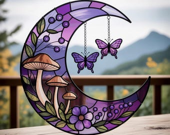 Peut inclure: Un croissant de lune en vitrail aux teintes violettes et lavande, orné de champignons, de baies et d'une fleur. Deux ornements papillon violets sont suspendus à des chaînes. L'œuvre est placée devant un arrière-plan extérieur flou.