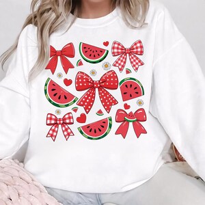 Pode incluir: Camisola branca com um padr&atilde;o de melancia e la&ccedil;o vermelho e branco.