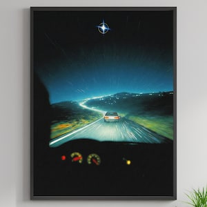 May include: A framed art print depicting a nighttime drive. The image shows a car on a winding road, with a starry sky above. The dashboard is visible in the foreground. The overall color palette is dark blue and green.
