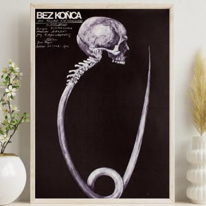 May include: Framed black and white poster with a human skull and spine connected to a curved, elongated shape. The poster has text at the top left, and is displayed in a light-coloured wooden frame.