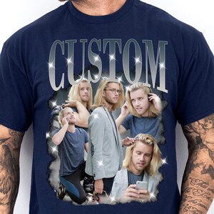 May include: Navy blue t-shirt with the word "CUSTOM" in a silver, sparkling font. The shirt features a collage of images of a person with long blonde hair in various poses. The images are surrounded by a sparkling border.