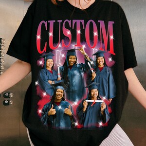 May include: Black t-shirt with a custom design featuring the word "CUSTOM" in a gradient red and purple font. The shirt displays a collage of graduates in blue gowns and caps, holding diplomas, with a red and white lightning bolt background.