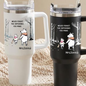 May include: Two tall stainless steel tumblers with handles and clear lids, one white and one black. Each features a graphic of two bears walking in a forest with the text "NEVER FORGET THE DIFFERENCE YOU MAKE" and the name "Mrs.Donna" printed below.