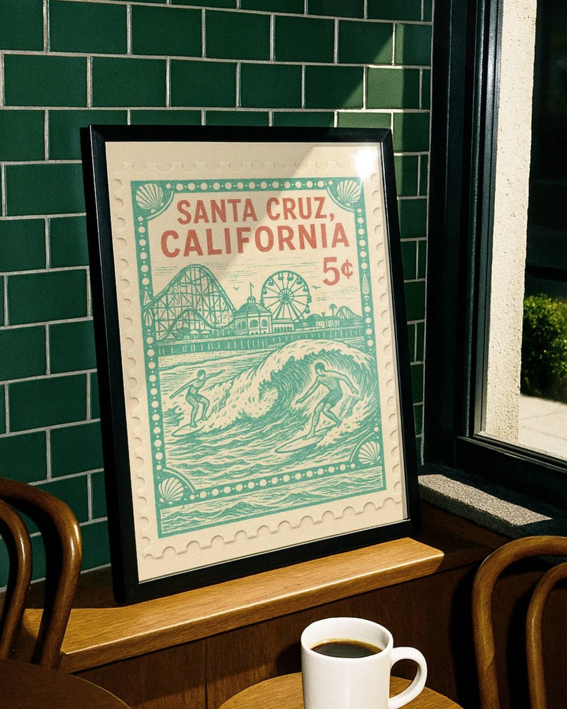 Może przedstawiać: Oprawiony wydruk z motywem vintage Santa Cruz, Kalifornia, z kolejką g&oacute;rską, diabelskim młynem i surferami. Grafika ma styl znaczka pocztowego z napisem "Santa Cruz, California 5&cent;". Grafika jest w czarnej ramie.
