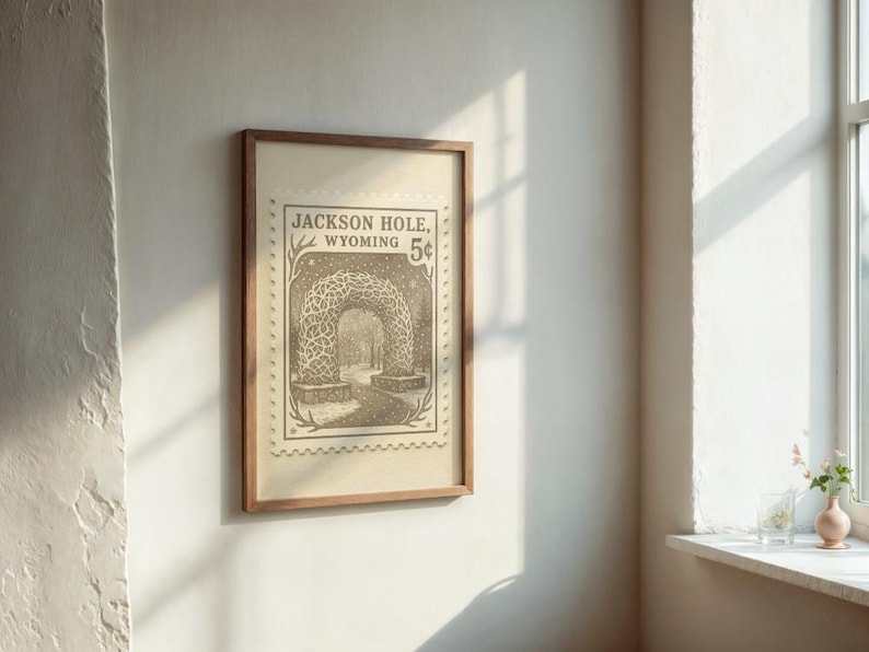 May include: Framed vintage-style print featuring a detailed illustration of an archway in Jackson Hole, Wyoming. The print has a sepia tone and is mounted in a wooden frame. The text "Jackson Hole, Wyoming 5&cent;" is visible.