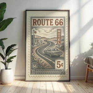 May include: Framed Route 66 vintage-style print. The artwork features a classic car driving on a winding road, with a gas station and motel sign. The print is in sepia tones with the text "ROUTE 66" and a 5&cent; price tag.