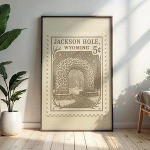 May include: Framed print featuring a sepia-toned illustration of an archway in Jackson Hole, Wyoming, resembling a vintage postage stamp. The artwork includes the text "Jackson Hole, Wyoming 5&cent;" and a detailed depiction of the archway.