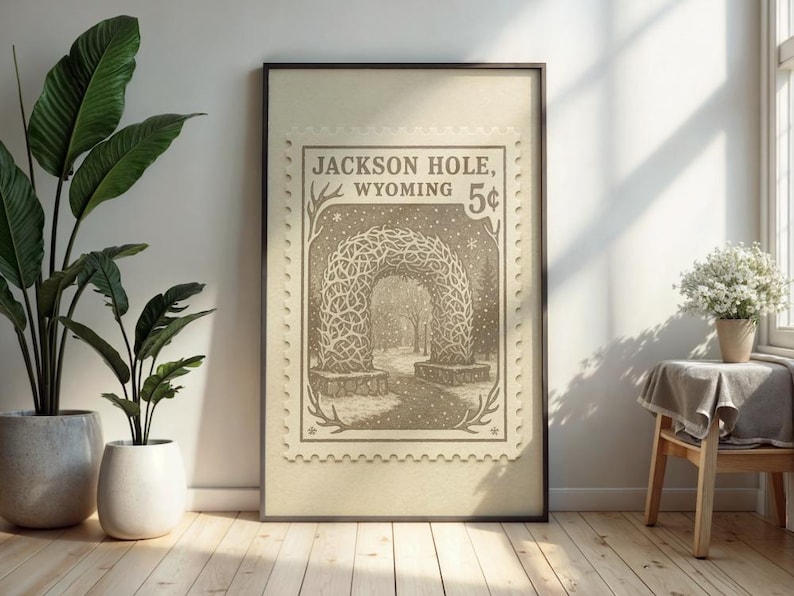May include: Framed print featuring a sepia-toned illustration of an archway in Jackson Hole, Wyoming, resembling a vintage postage stamp. The artwork includes the text "Jackson Hole, Wyoming 5&cent;" and a detailed depiction of the archway.
